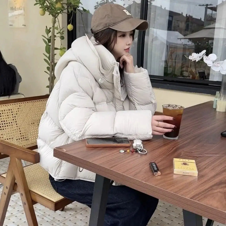 Weisse Steppjacke mit Kapuze, legerer Stil, Frau sitzt am Tisch, IsabellBoutique030