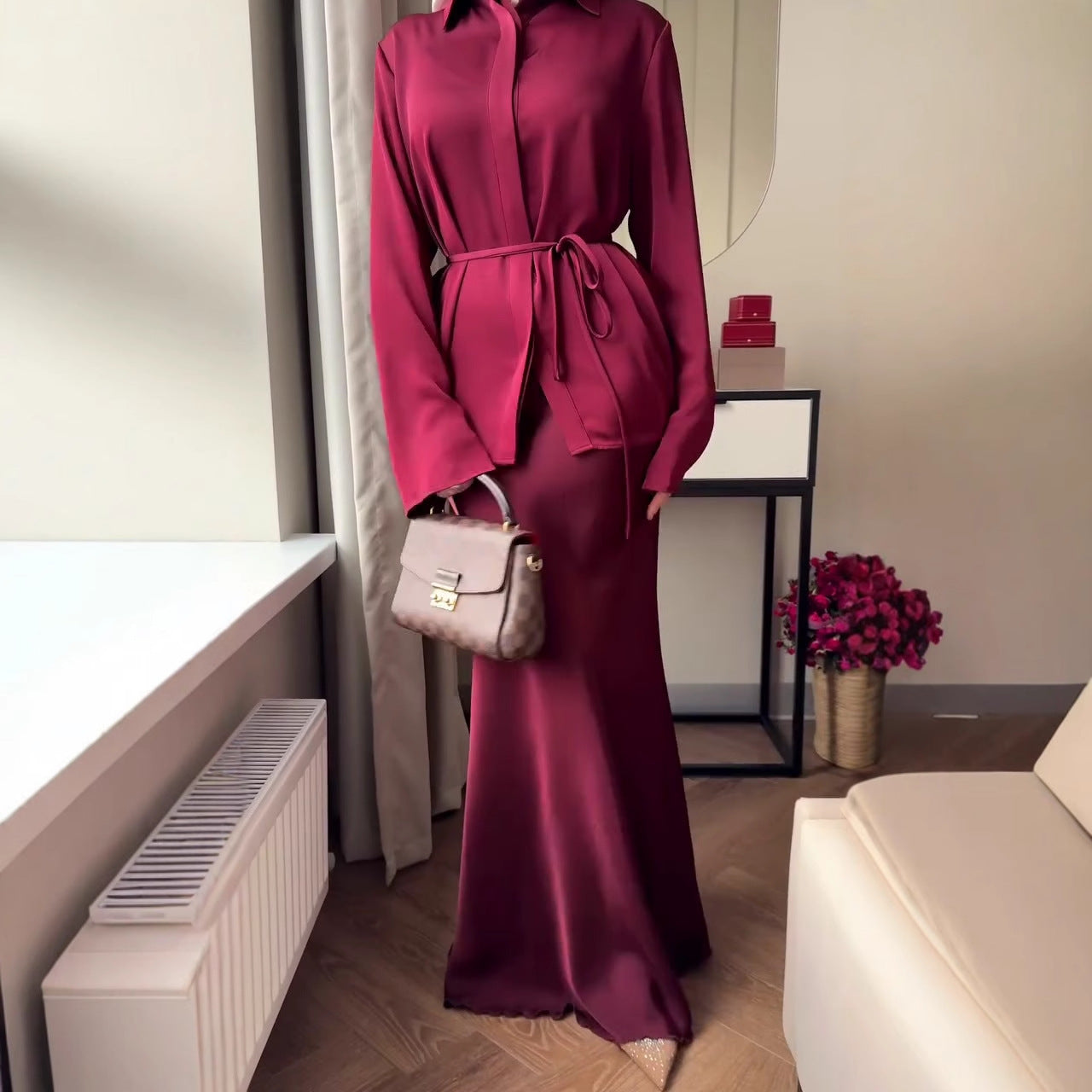 Die Kleidung ist im modischen Modest-Fashion-Stil gehalten, kombiniert mit einem braunen Hijab und einem schmalen Taillengürtel.