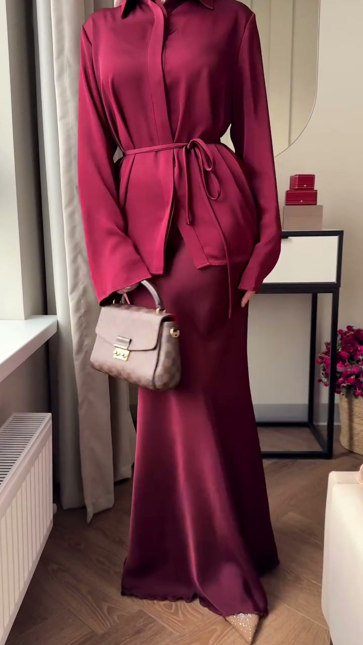 Die Kleidung ist im modischen Modest-Fashion-Stil gehalten, kombiniert mit einem braunen Hijab und einem schmalen Taillengürtel.