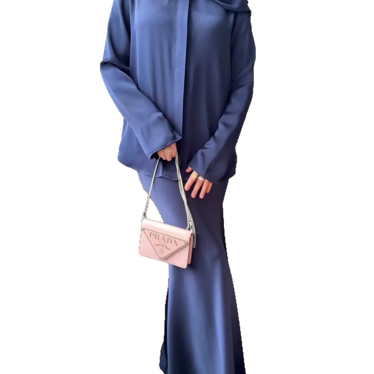 Die Kleidung ist im modischen Modest-Fashion-Stil gehalten, kombiniert mit einem braunen Hijab und einem schmalen Taillengürtel.