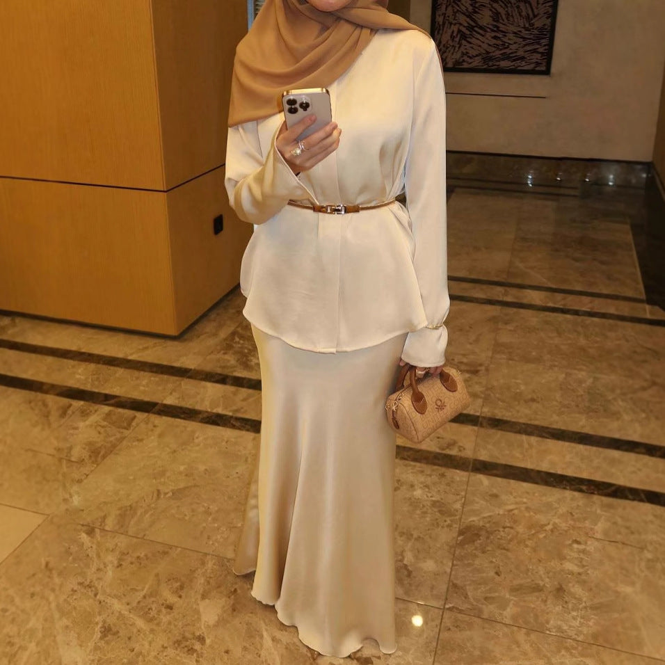 Die Kleidung ist im modischen Modest-Fashion-Stil gehalten, kombiniert mit einem braunen Hijab und einem schmalen Taillengürtel.